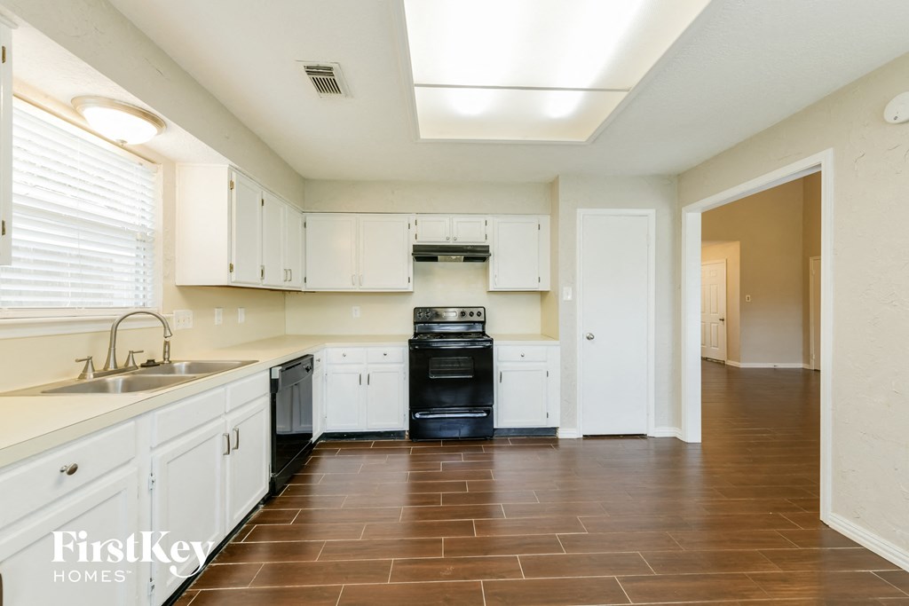 an empty kitchen with white cabinets and a black stove