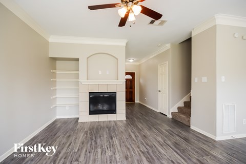 A spacious living room with a fireplace and a ceiling fan.