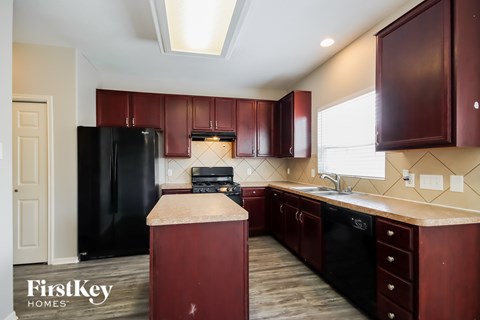 A kitchen with dark wood cabinets and a black refrigerator.