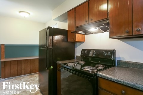 a kitchen with black appliances and wooden cabinets and a black refrigerator
