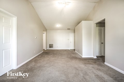 a spacious living room with carpet and white walls