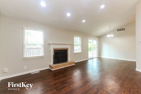 A spacious room with a fireplace and wood flooring.