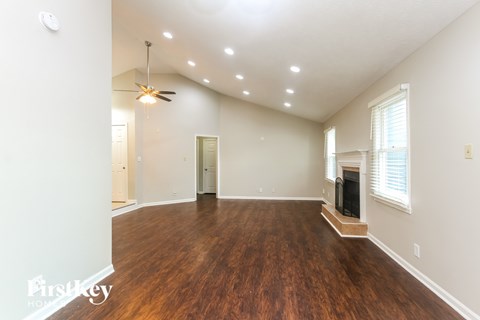 A spacious room with wood flooring and a fireplace.