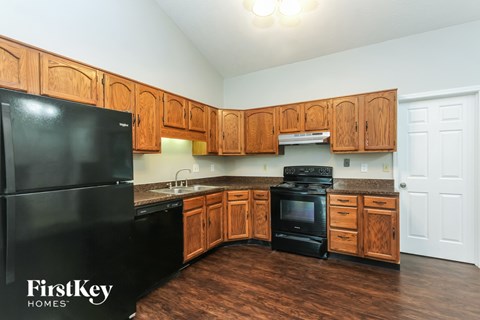 A kitchen with wooden cabinets and a black fridge.