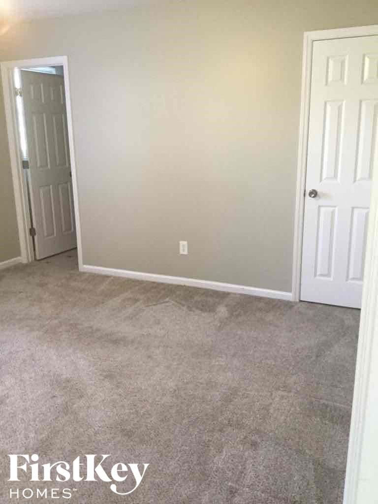 a carpeted room with a white door and a gray wall
