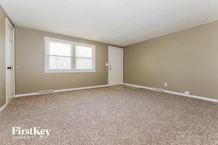 A room with a carpeted floor and two windows.