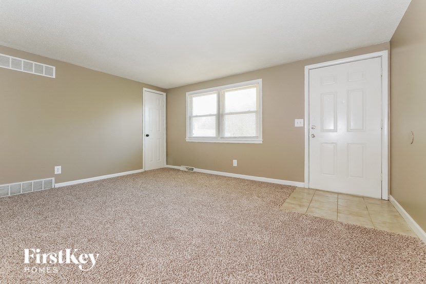 A room with a carpeted floor and two doors.