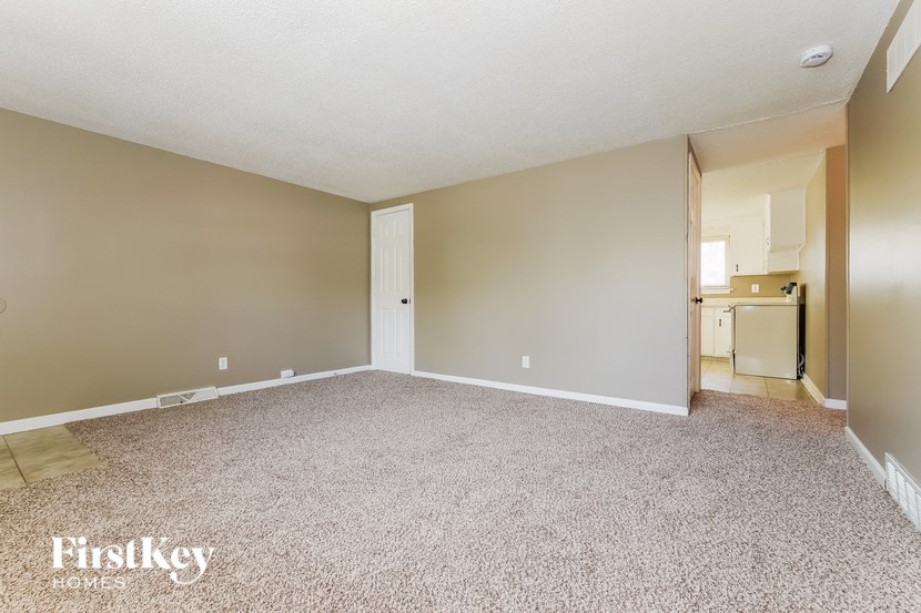 A spacious room with a carpeted floor and a doorway leading to another room.