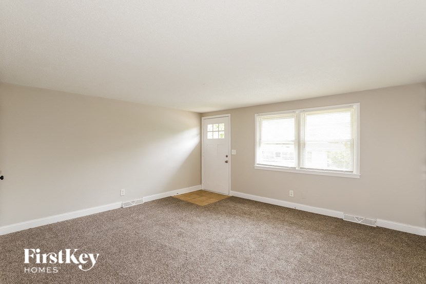 a bedroom with carpet and a door and two windows