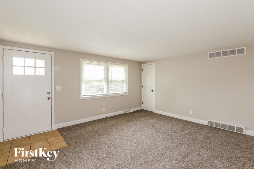 a bedroom with a carpeted floor and a door and two windows