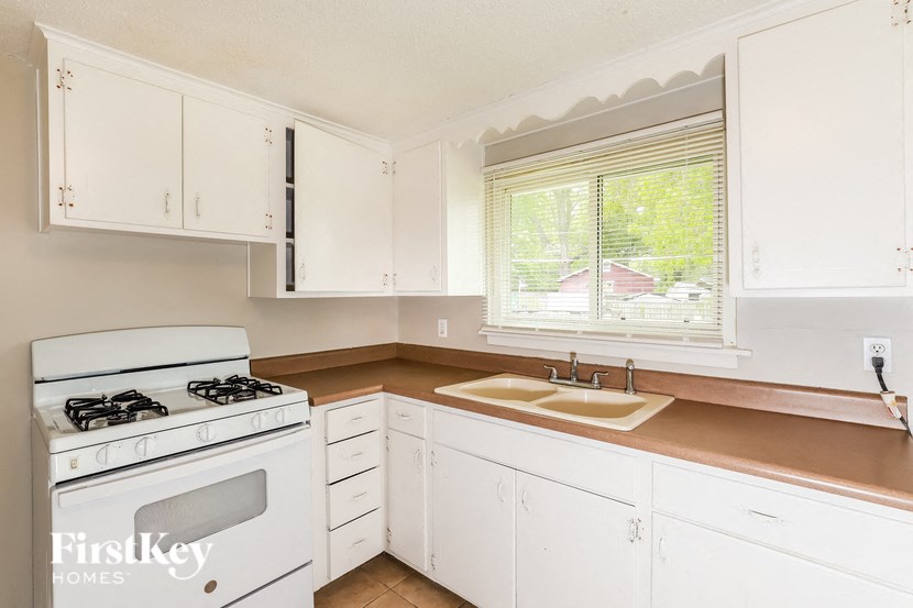 a kitchen with white cabinets and a white stove and sink