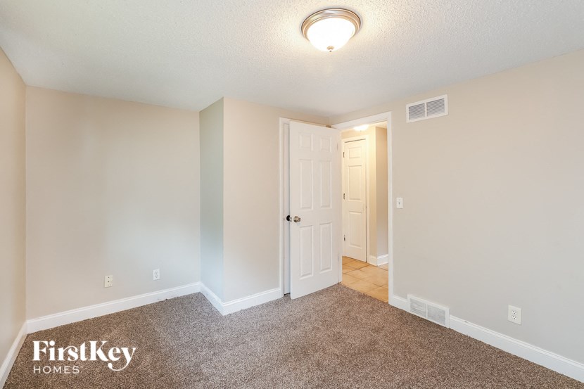 a spacious living room with carpet and a door to a hallway