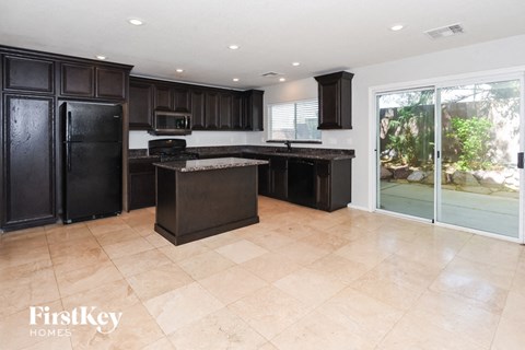 A kitchen with black cabinets and a black refrigerator.