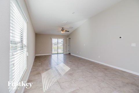 A spacious room with a fan and sliding glass doors.