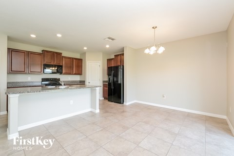 A kitchen with a black refrigerator and wooden cabinets.