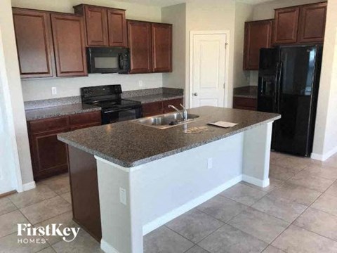 A kitchen with brown cabinets and a black refrigerator.