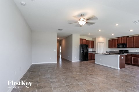 A spacious kitchen with brown cabinets and a black refrigerator.
