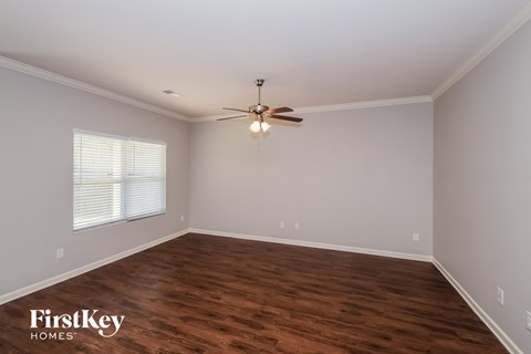 A room with a ceiling fan and wooden flooring.