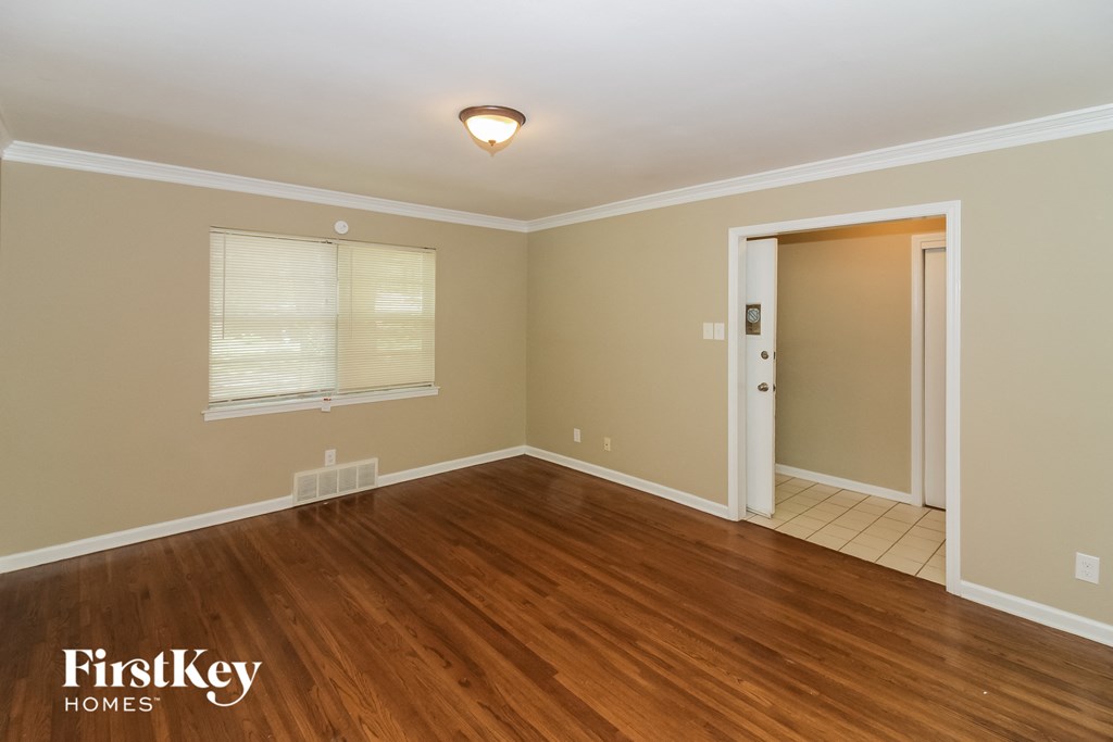 A room with wooden floors and a door leading to another room.