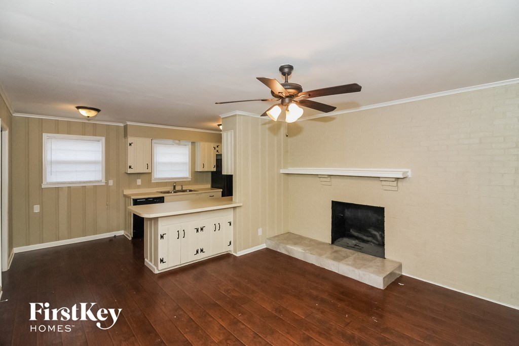A well-lit room with a fireplace and a ceiling fan.