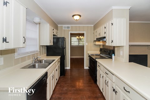 A kitchen with white cabinets and a black refrigerator.
