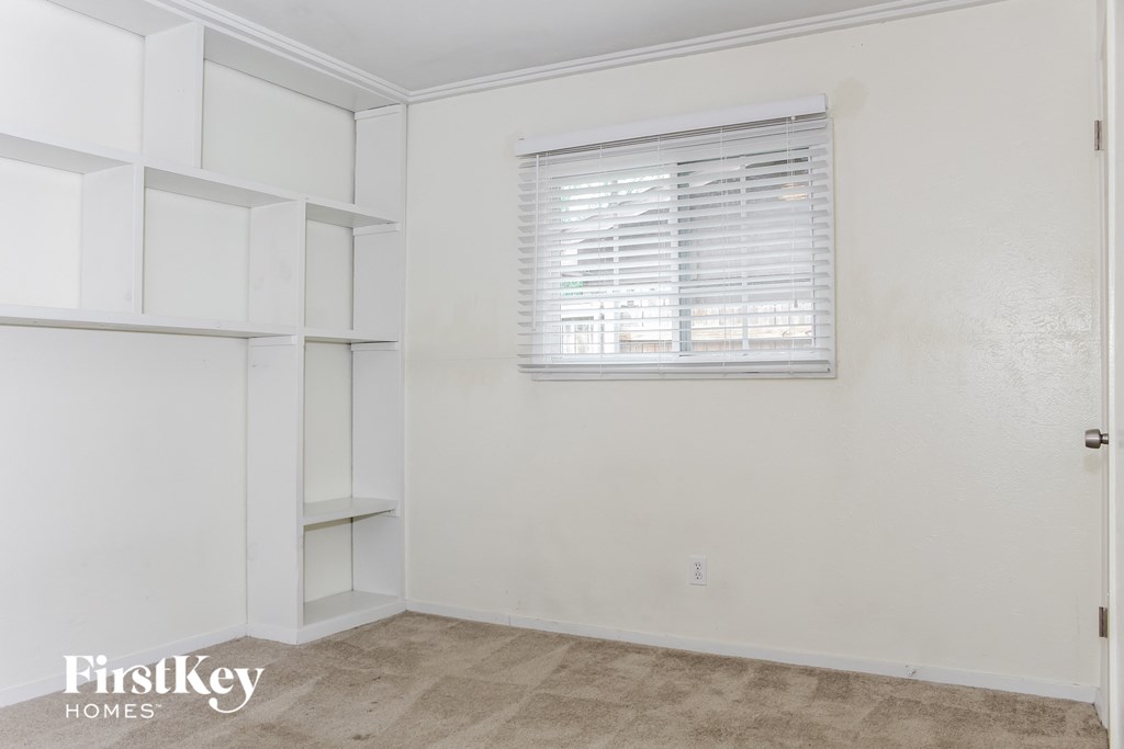 a bedroom with white walls and white shelves and a window