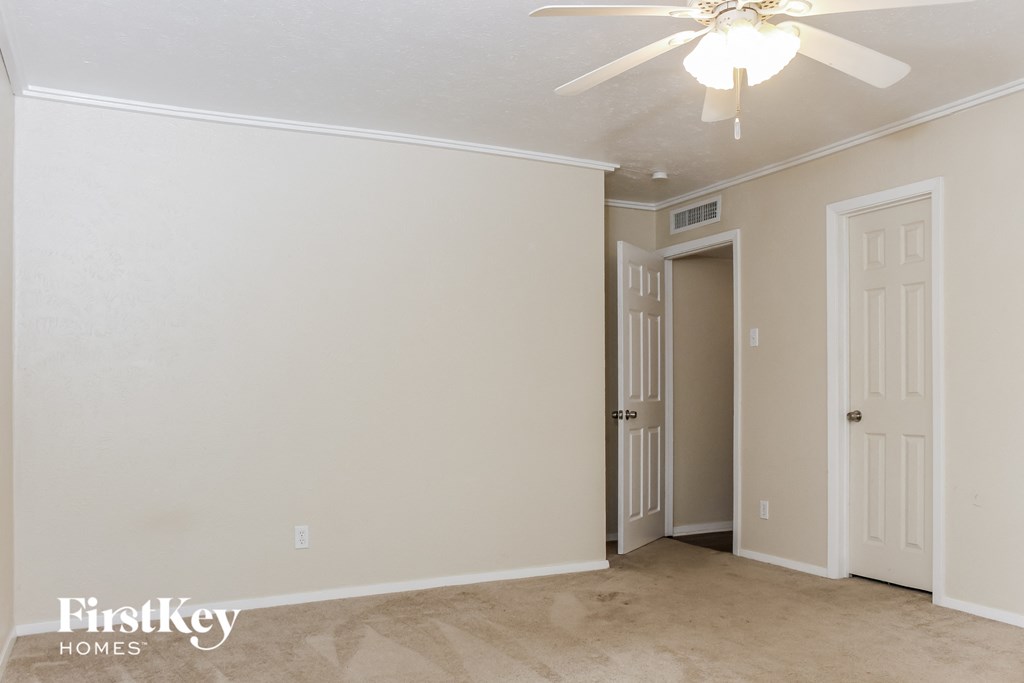 a bedroom with a white wall and a ceiling fan