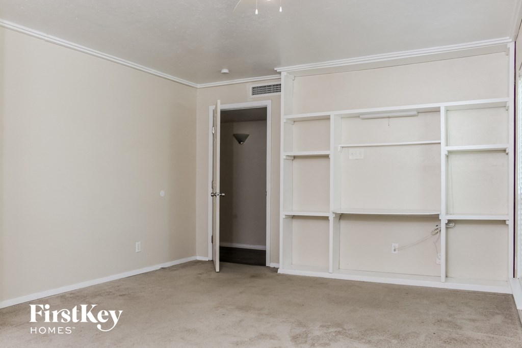 a bedroom with white shelves and a closet and a door