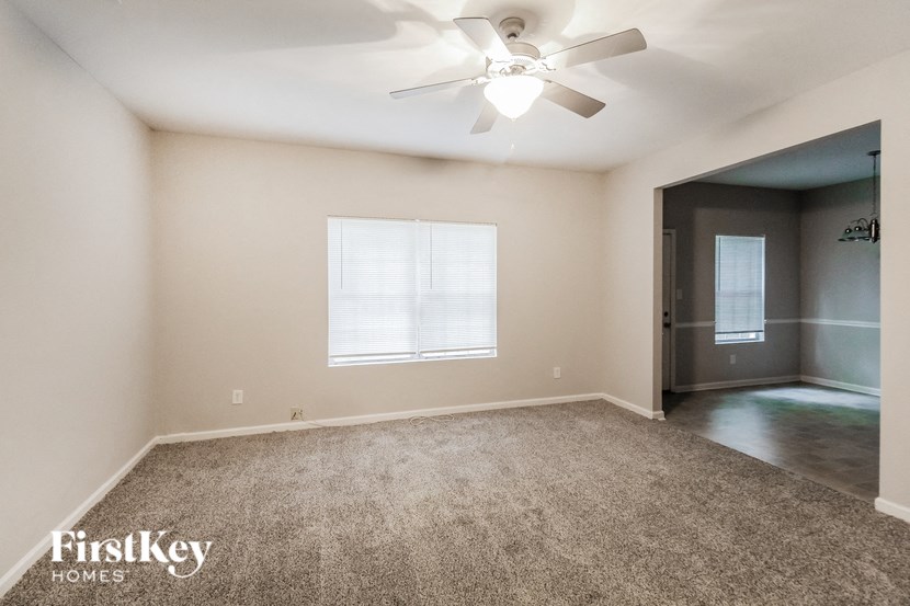 an empty living room with carpet and a ceiling fan