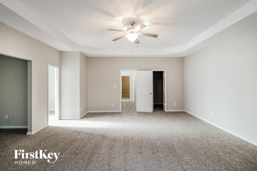 a spacious living room with carpet and a ceiling fan