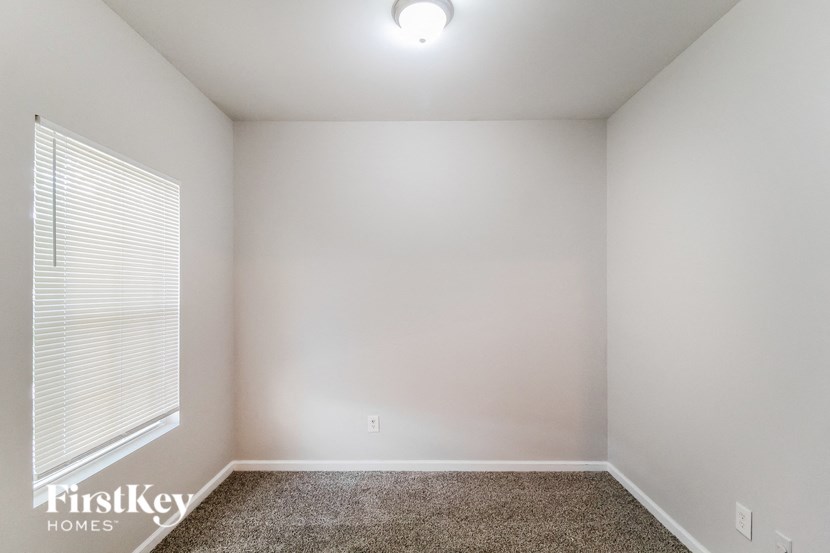 a bedroom with white walls and a window and a carpeted floor