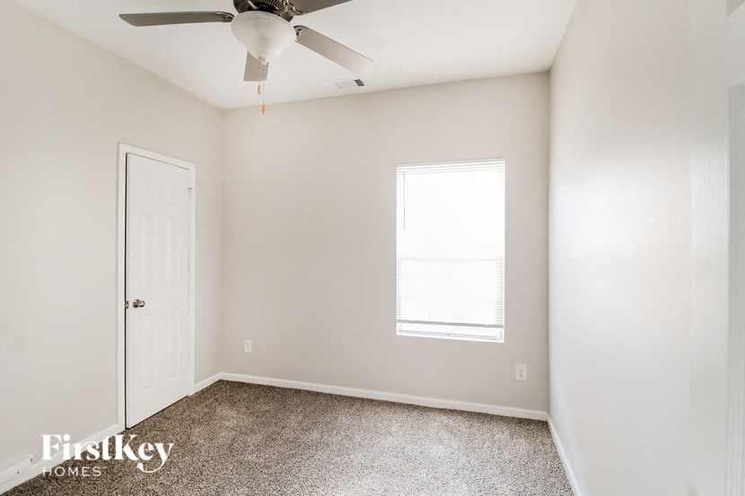 a bedroom with white walls and a ceiling fan