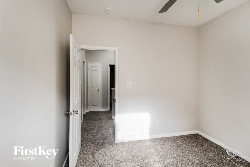 a bedroom with white walls and a white door and a ceiling fan