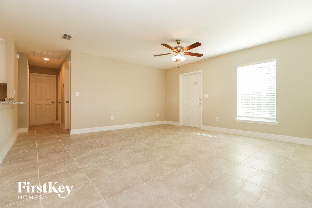 A spacious room with a ceiling fan and tiled flooring.