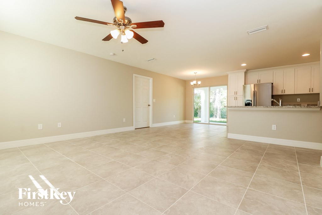 A spacious living room with a ceiling fan and tiled flooring.
