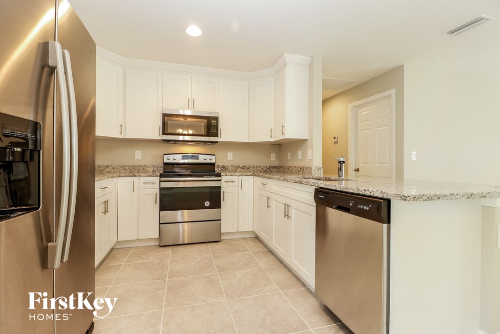 A kitchen with a refrigerator, microwave, oven, and dishwasher.
