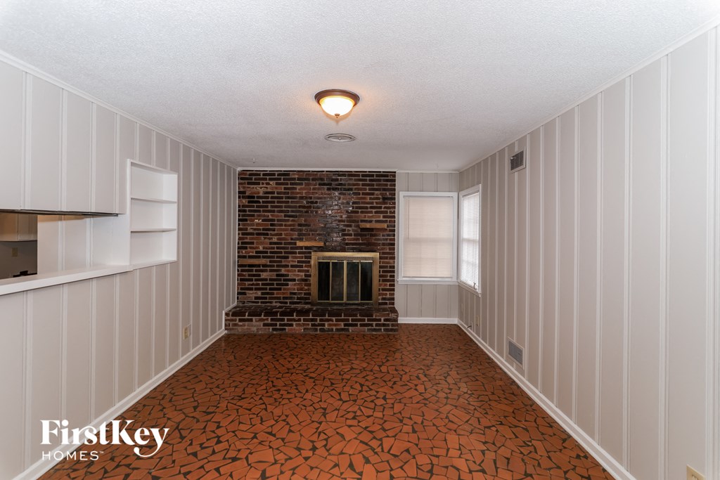 A room with a brick fireplace and wooden paneling.