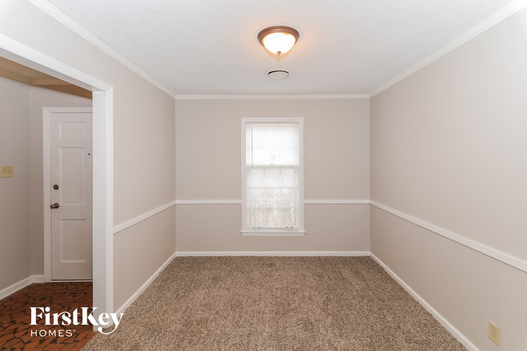 A room with a carpeted floor and a window with blinds.