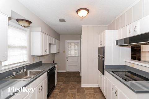A kitchen with white cabinets and a black stove top oven.