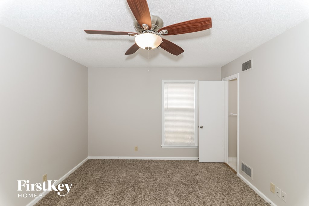 A room with a ceiling fan and a carpeted floor.