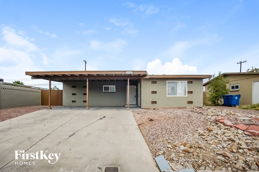 A house with a concrete driveway and a gravel area in front of it.