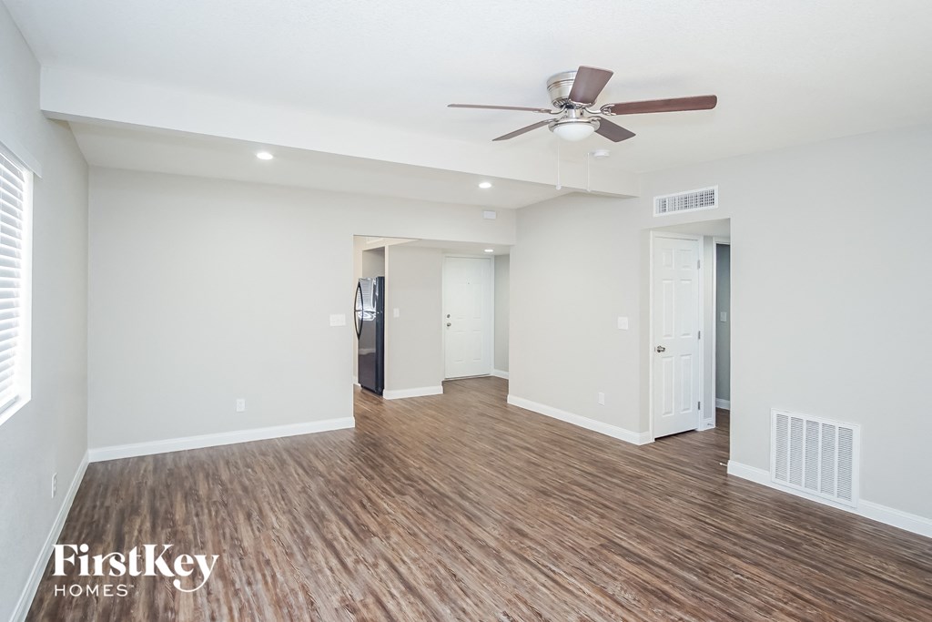 A spacious room with a ceiling fan and wooden flooring.