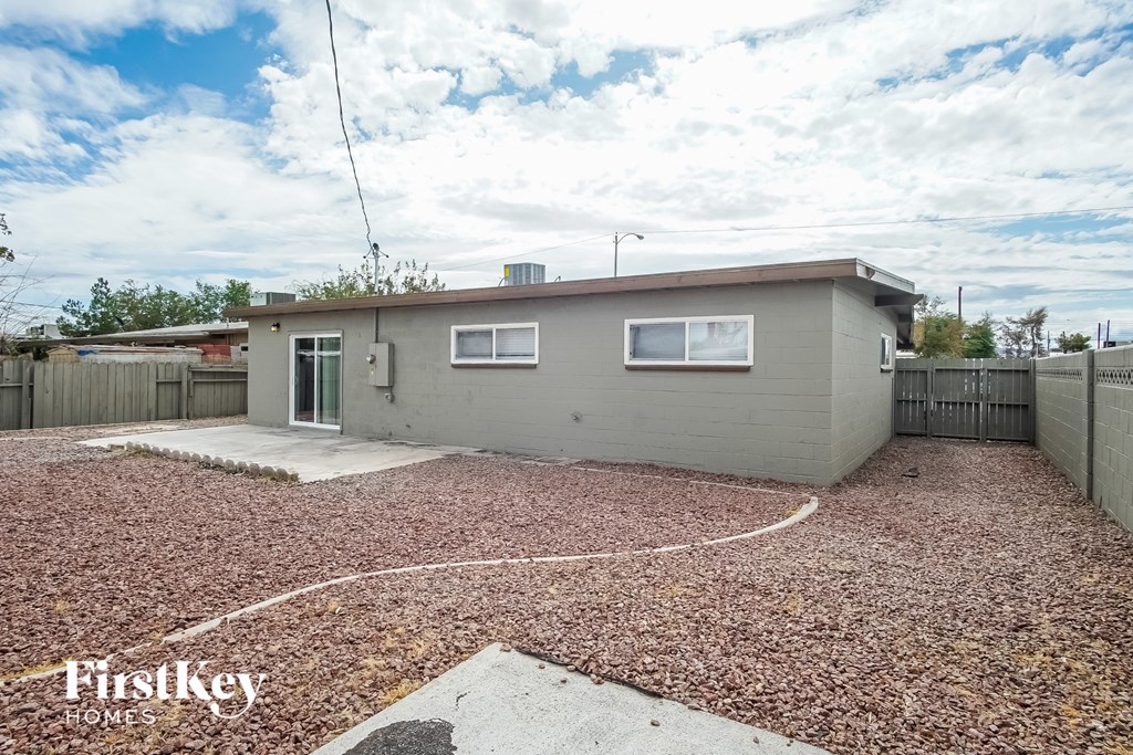 A house with a grey exterior and a gravel driveway is for sale.