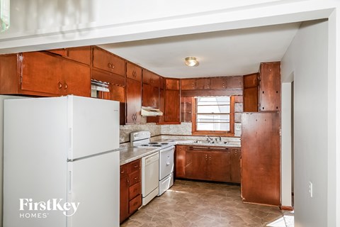 A kitchen with a white fridge and brown cabinets.