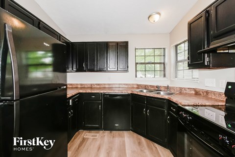 A kitchen with black cabinets and a wooden island.
