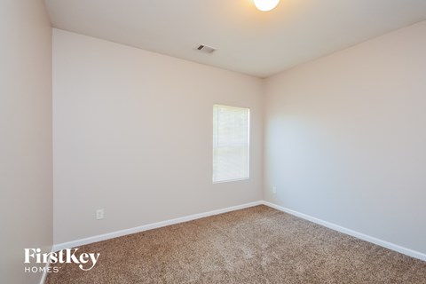 a bedroom with white walls and carpet and a window