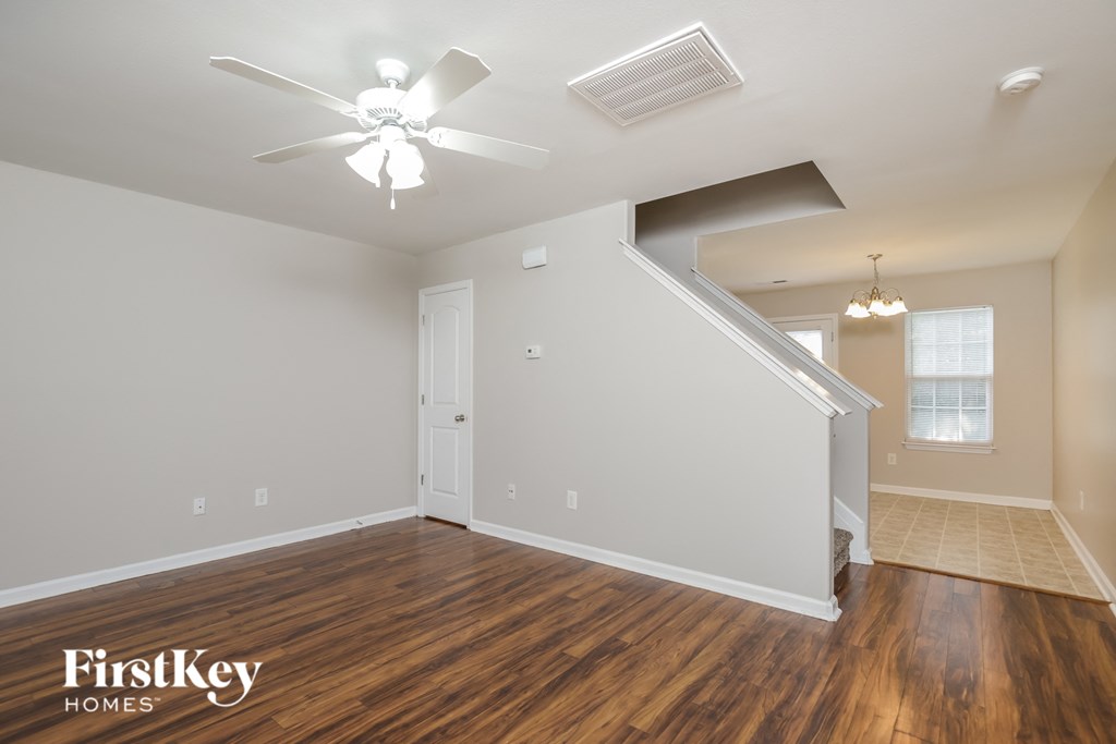 the spacious living room with hardwood flooring and a ceiling fan