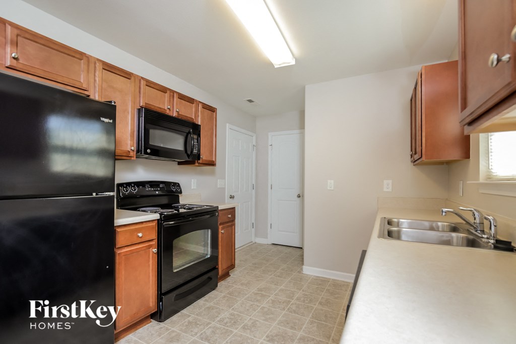 a kitchen with black appliances and white countertops and wooden cabinets