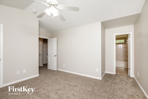 a master bedroom with carpet and a ceiling fan