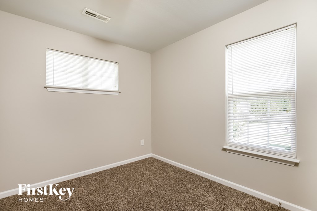 a bedroom with a carpeted floor and two windows